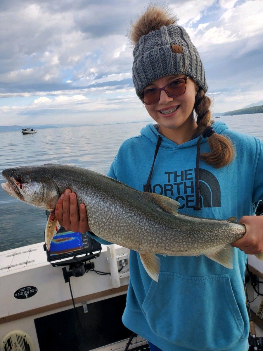A young girl is holding a large fish on a boat.