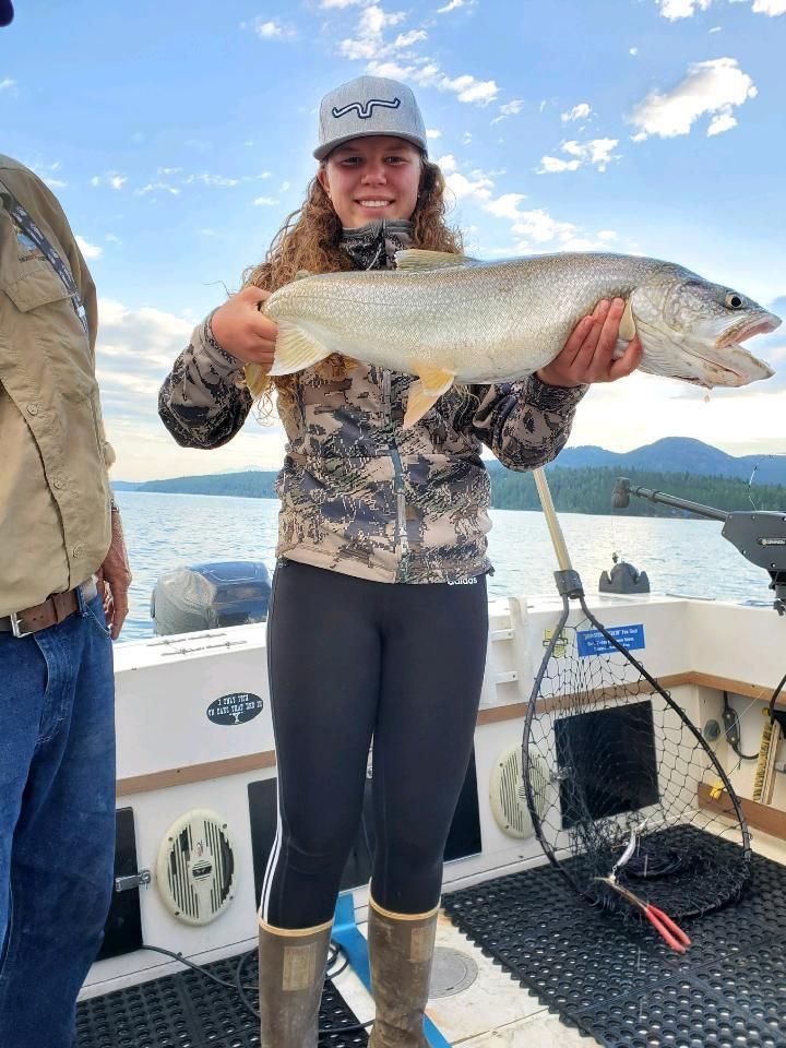 A woman is holding a large fish on a boat.