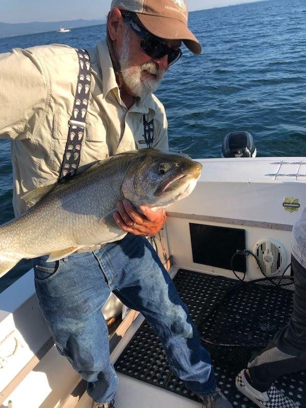 A man is holding a large fish on a boat