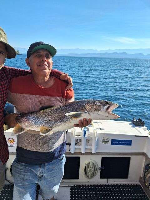 Two men on a boat holding a large fish