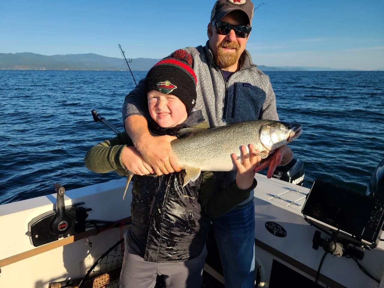 A man and a boy are holding a fish on a boat.