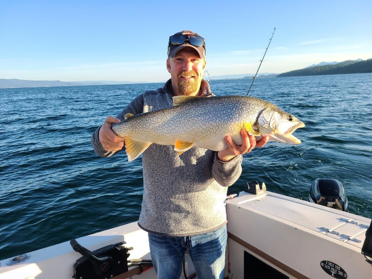 A man is holding a large fish on a boat in the water.