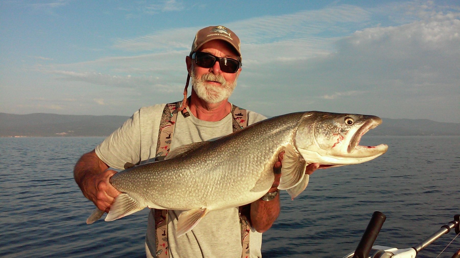 A man is holding a large fish in his hands on a boat.
