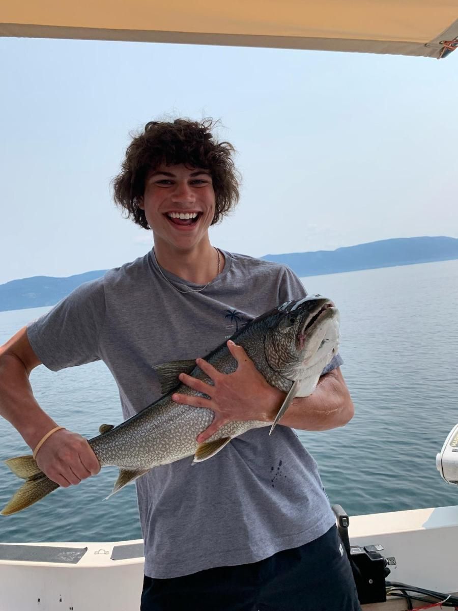 A young man is holding a large fish on a boat.