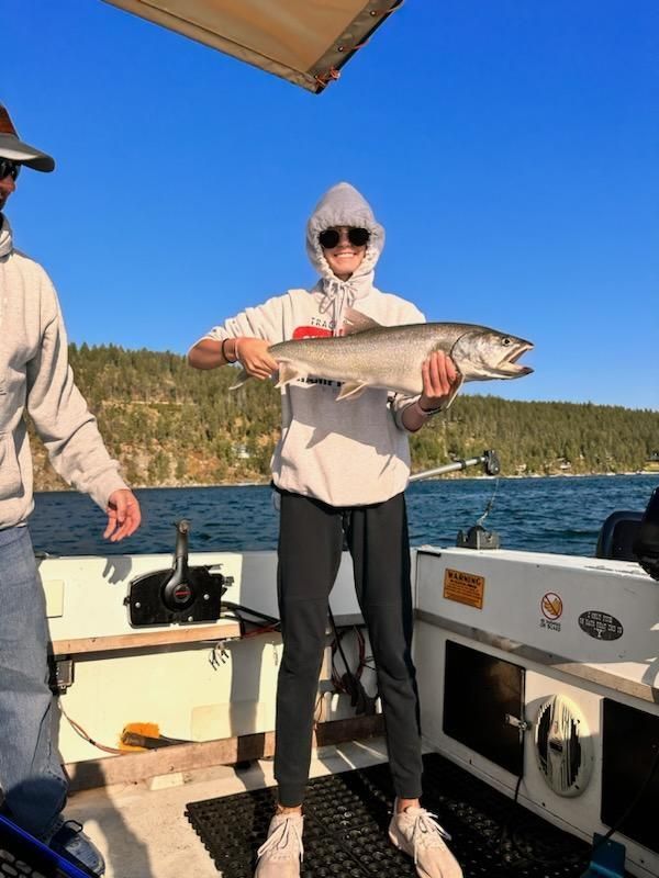 A man and a woman are standing on a boat holding a large fish.