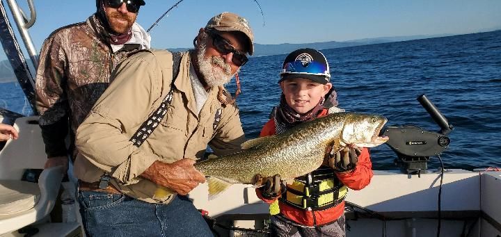 A man and a boy are holding a large fish on a boat.