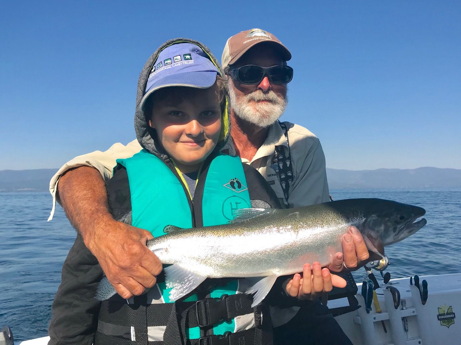 A man and a boy are holding a large fish on a boat.