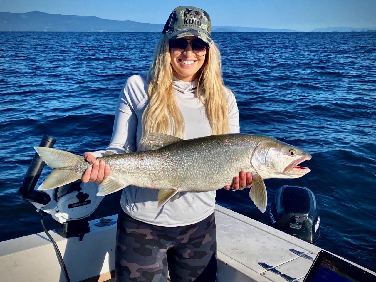A woman is holding a large fish on a boat.