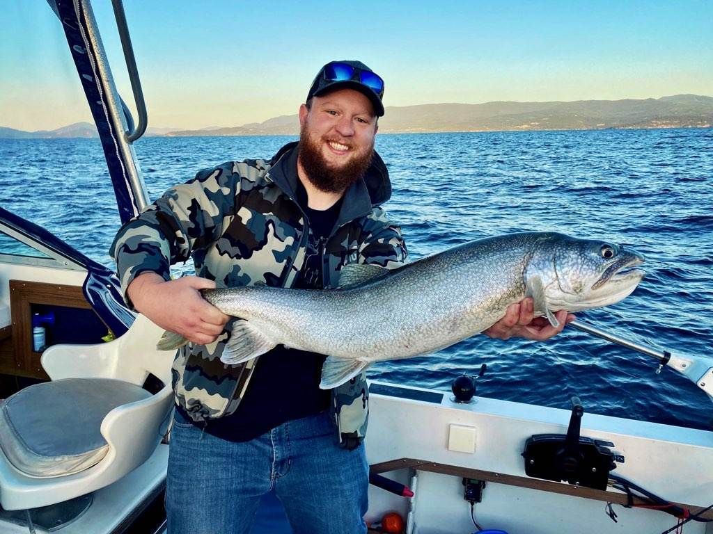 A man is holding a large fish on a boat in the ocean.
