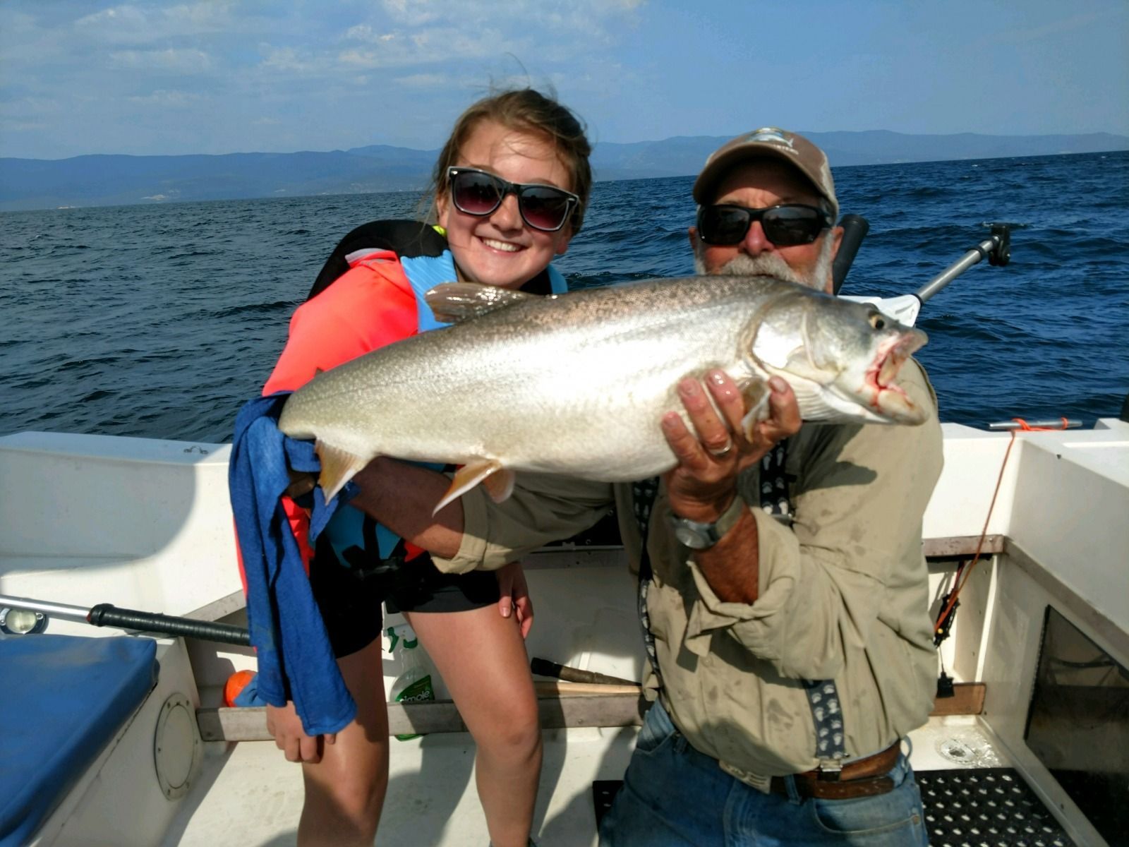 A man and a girl on a boat holding a fish