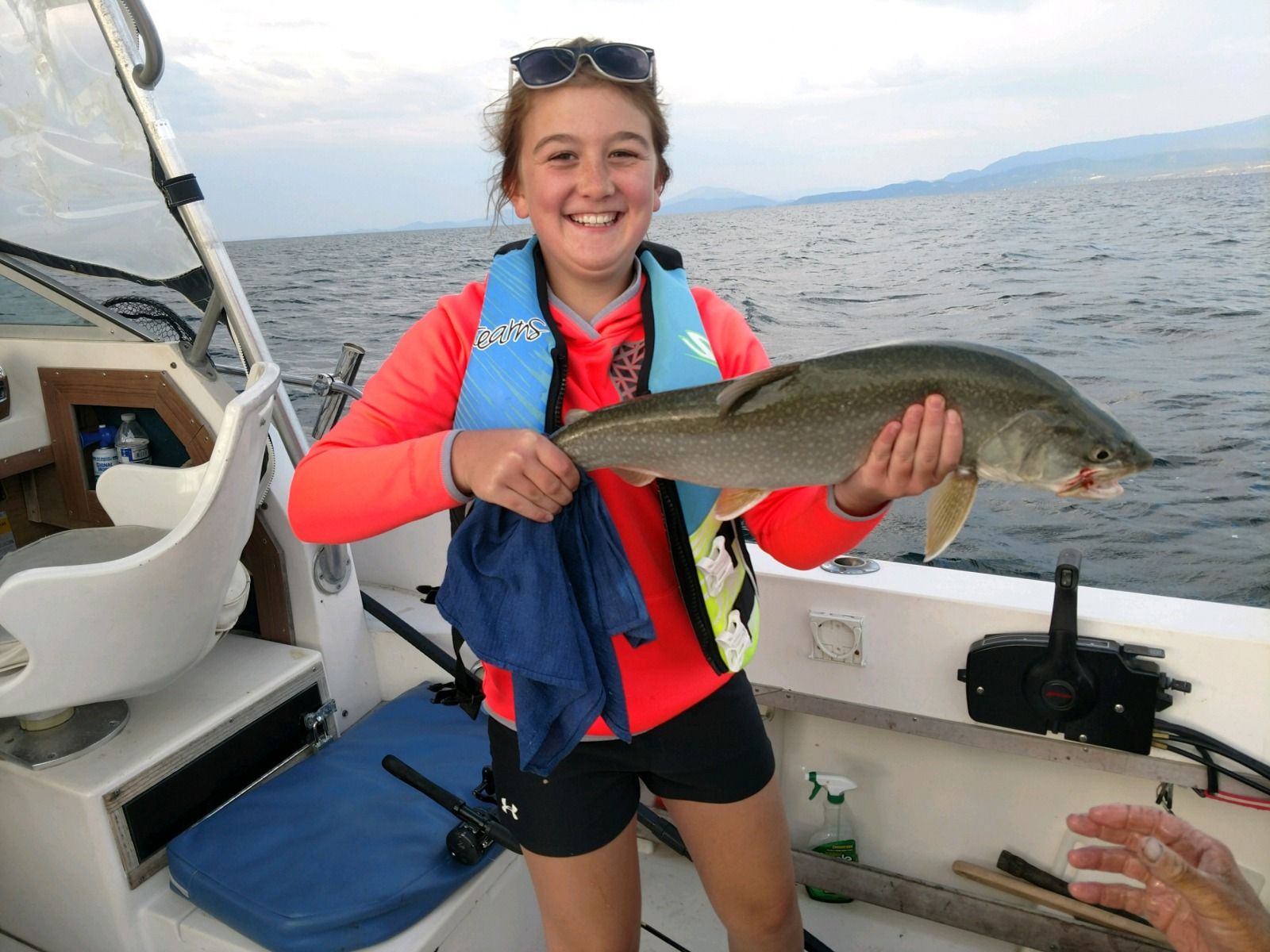 A young girl is holding a fish on a boat.