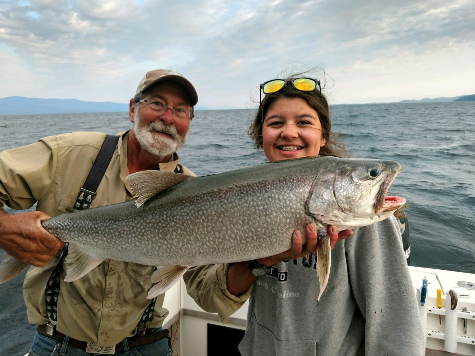 A man and a woman are holding a large fish on a boat.
