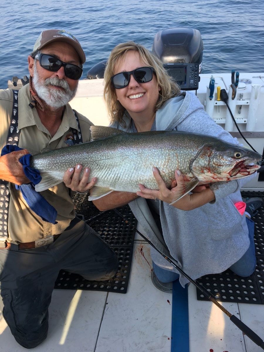 A man and a woman are holding a large fish on a boat.
