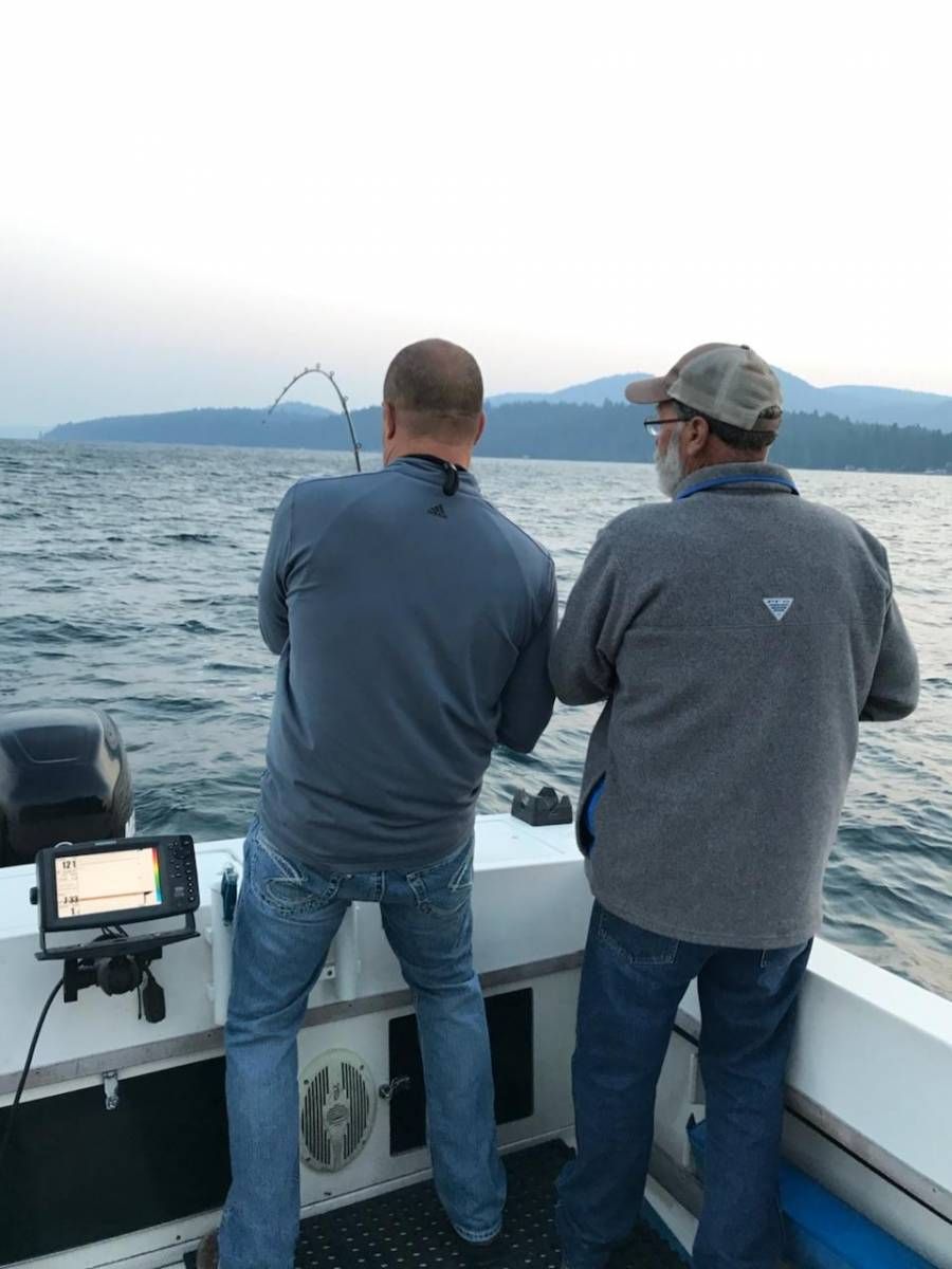 Two men are standing on a boat looking at the water