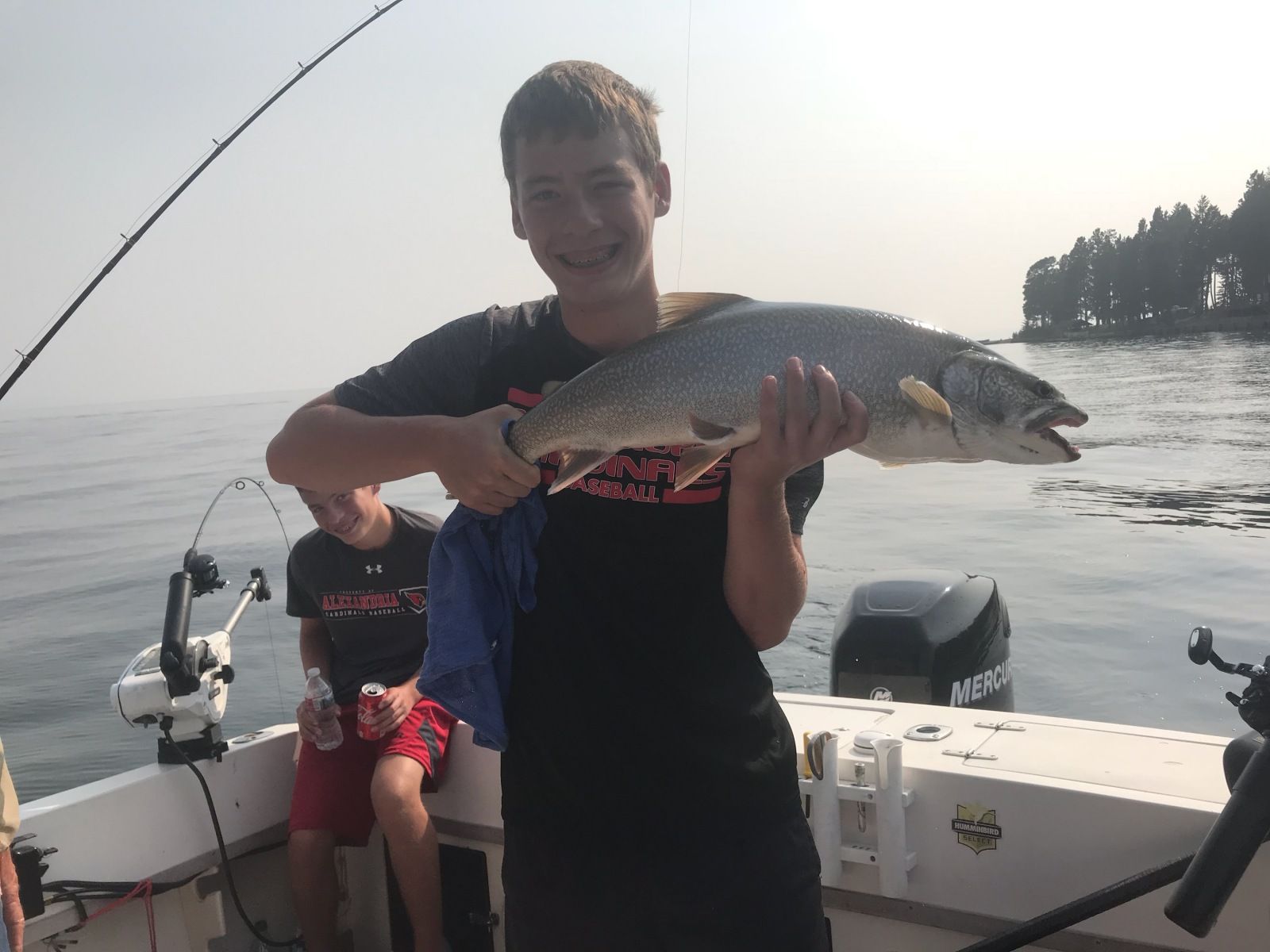 A young boy is holding a large fish on a boat.