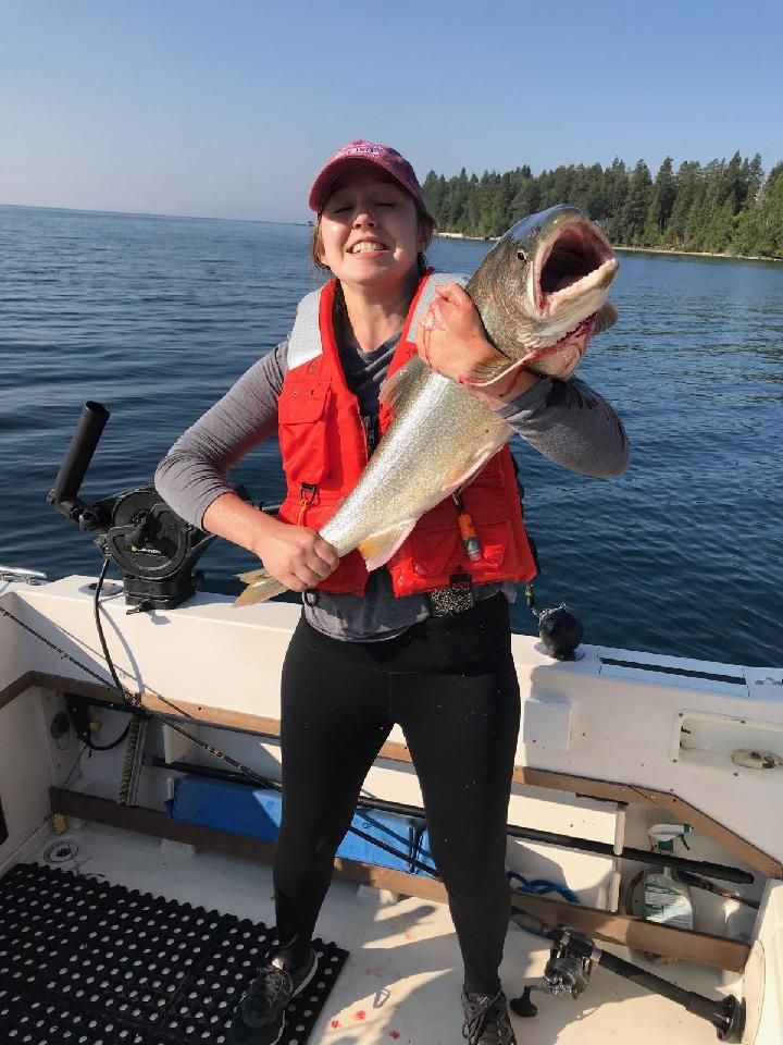 A woman is holding a large fish on a boat.