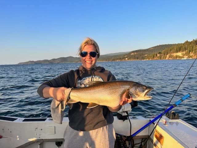 A woman is holding a large fish on a boat.