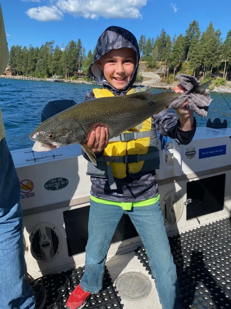 A young boy is holding a large fish on a boat.