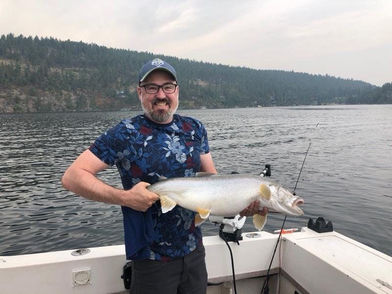 A man is holding a large fish on a boat.