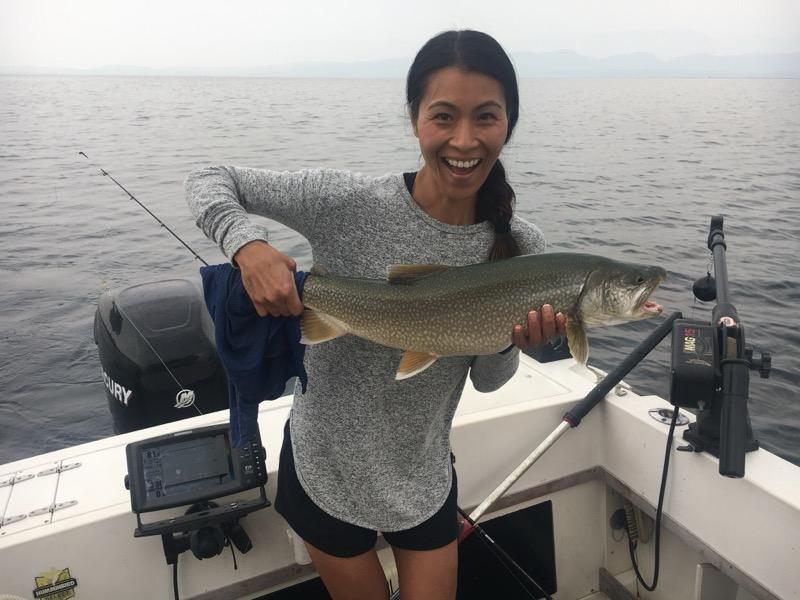 A woman is holding a large fish on a boat.