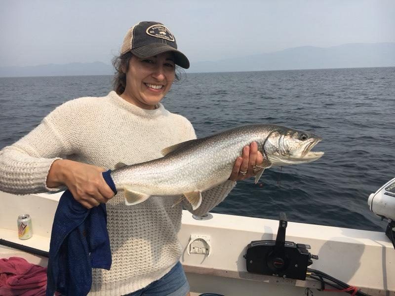 A woman is holding a large fish on a boat.