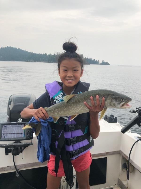 A young girl is holding a large fish on a boat.