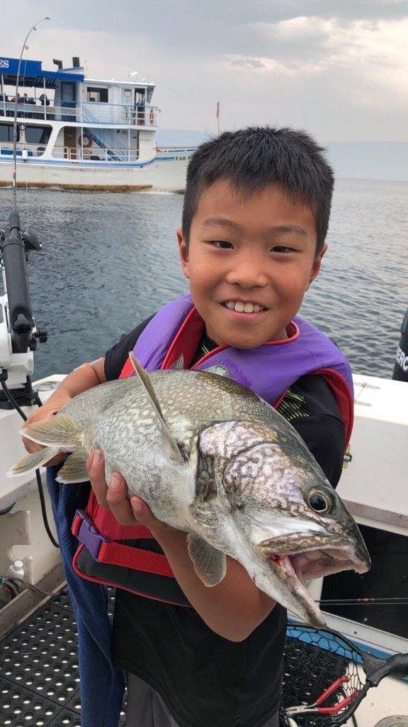 A young boy is holding a large fish on a boat.