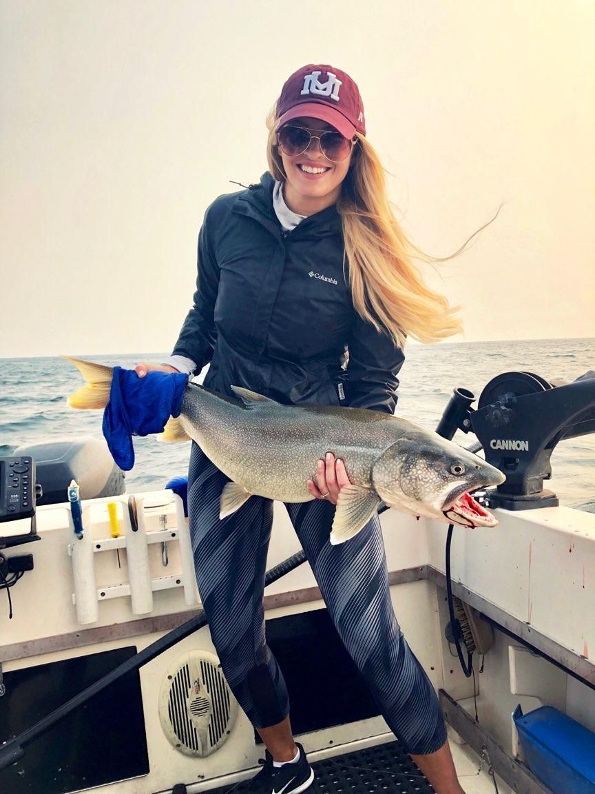 A woman is holding a large fish on a boat.