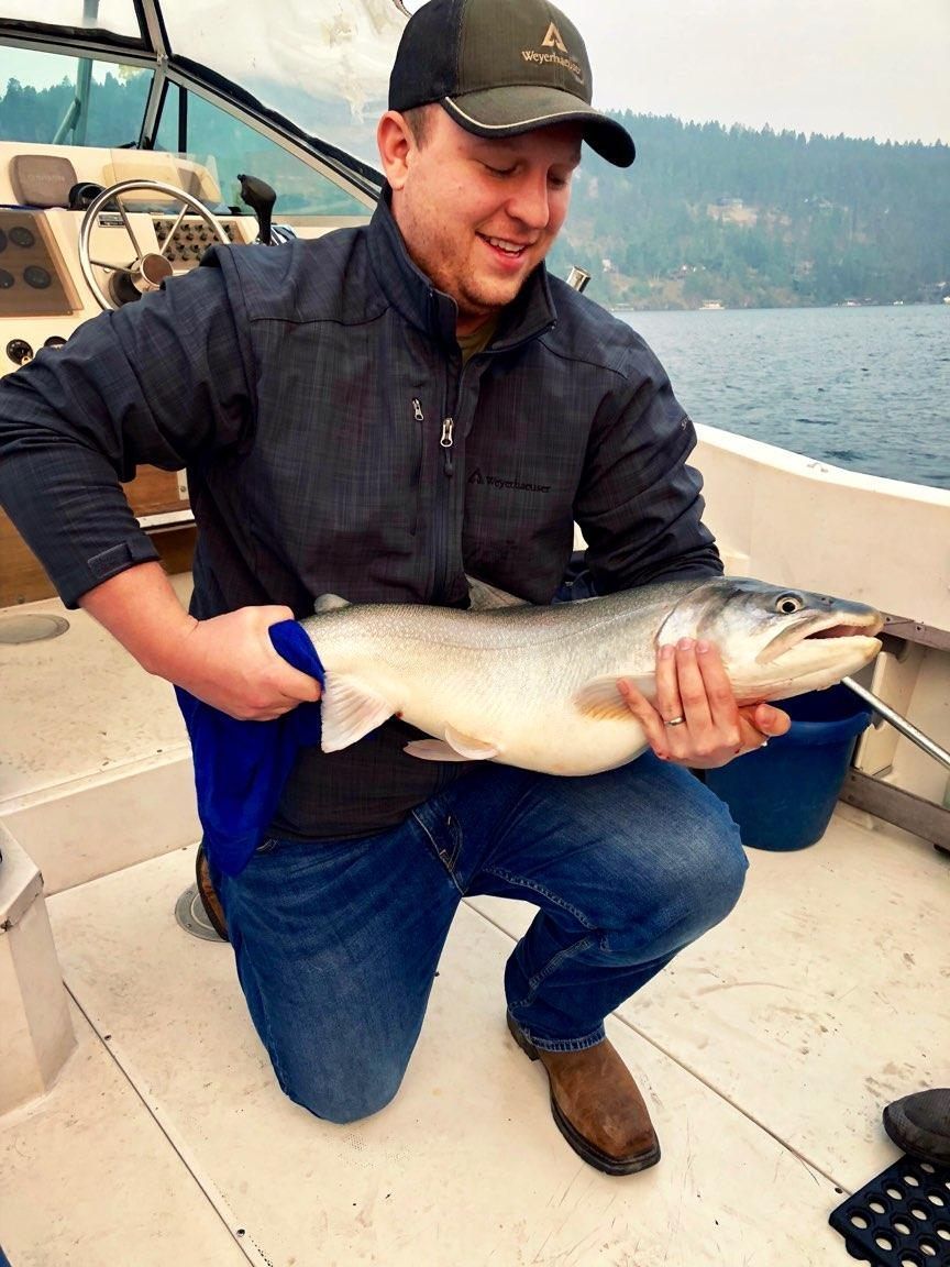 A man is kneeling on a boat holding a large fish