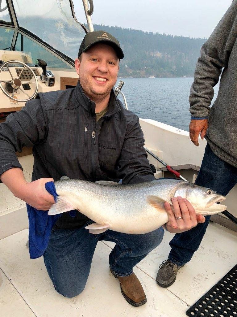 A man is kneeling down on a boat holding a large fish.