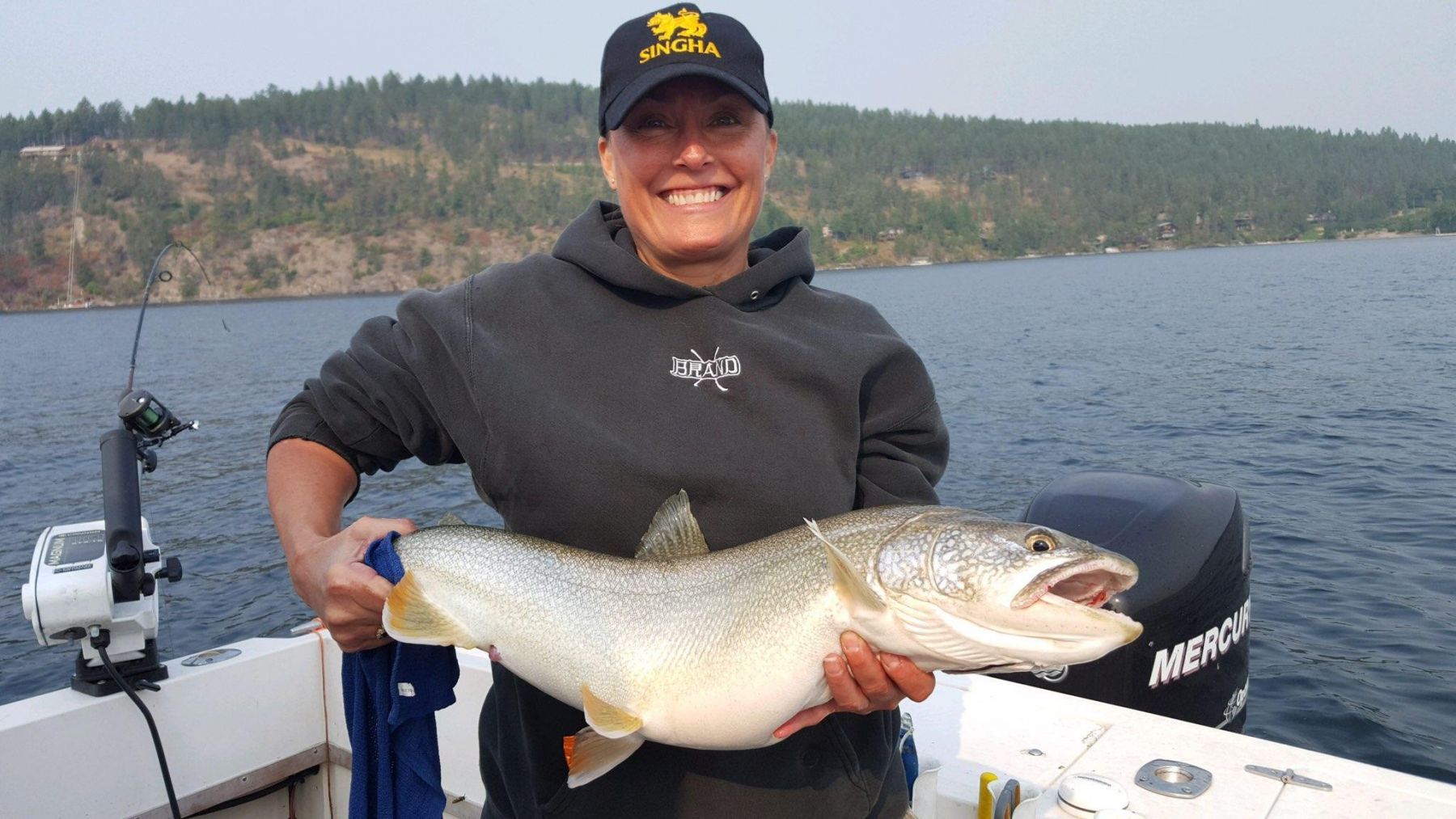 A woman is holding a large fish on a boat.