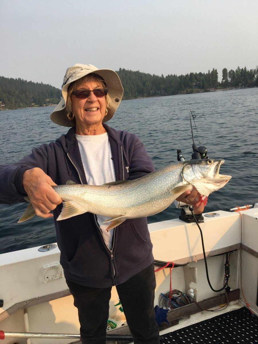 A woman is holding a large fish on a boat.