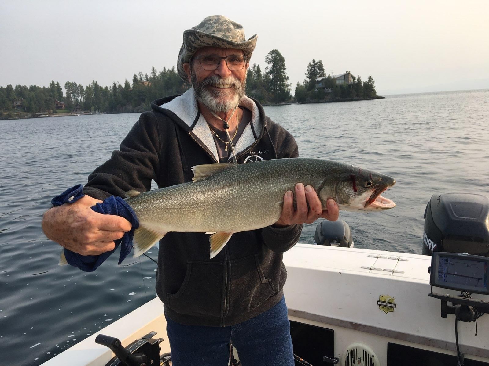 A man is holding a large fish on a boat.
