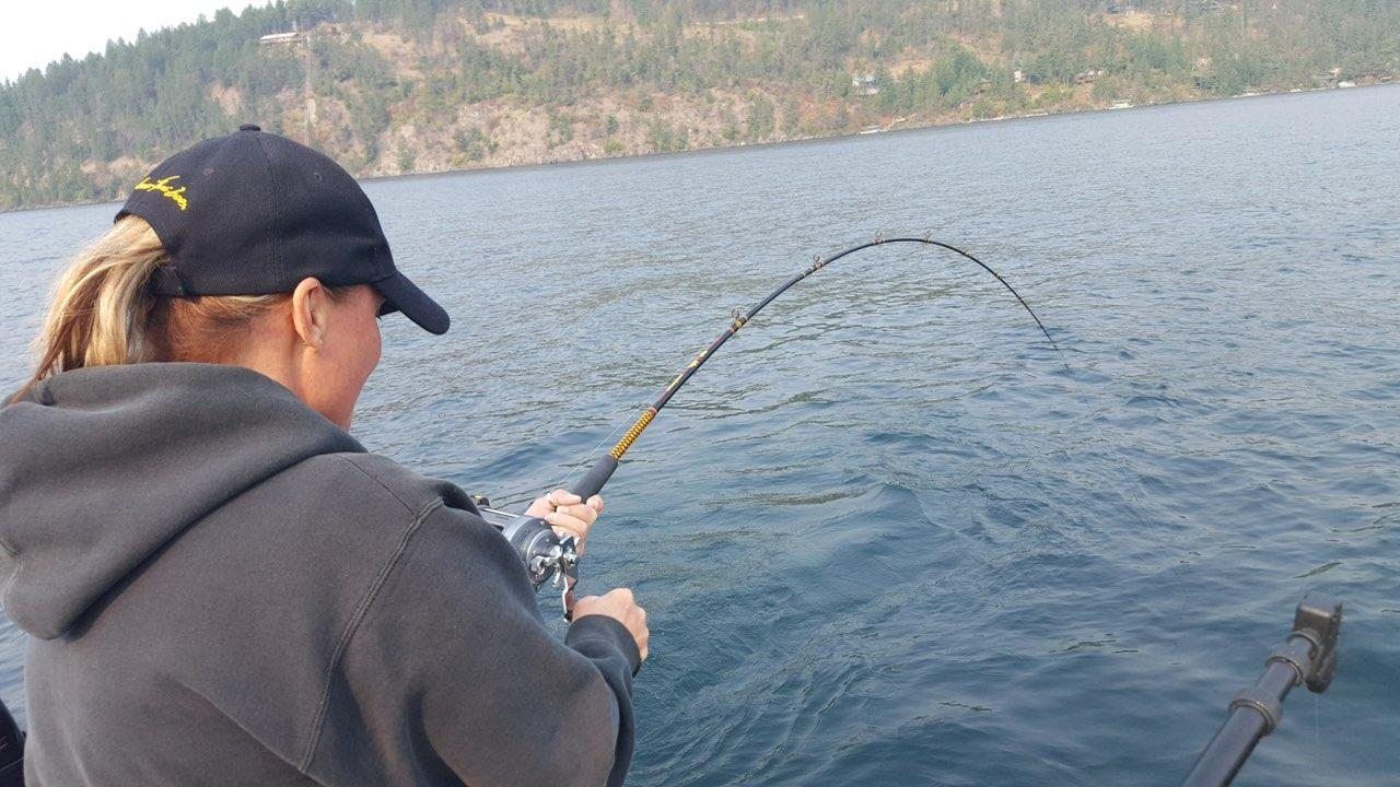 A woman is fishing on a boat in the water.