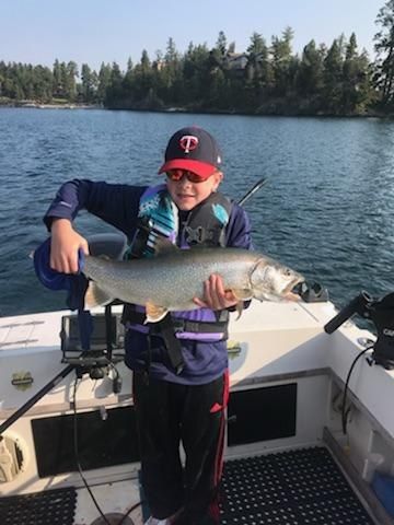 A young boy is holding a large fish on a boat.