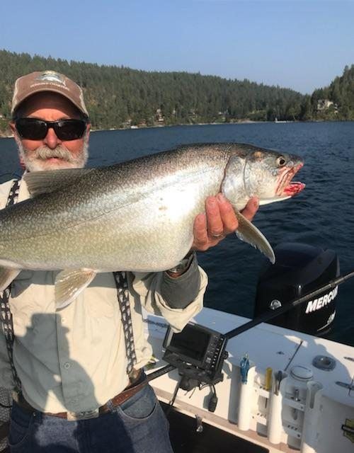 A man holding a fish in front of a mercury boat