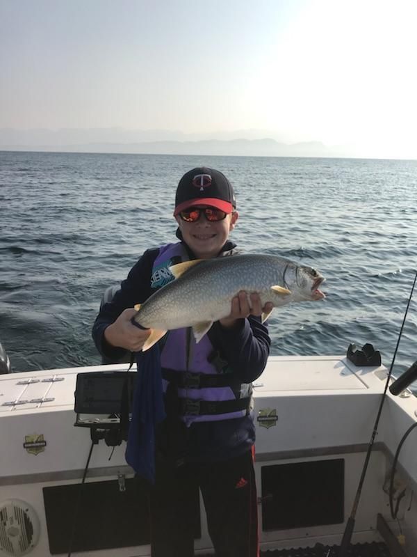 A man is holding a fish on a boat in the ocean.
