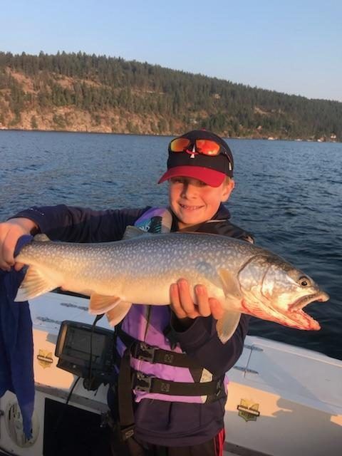 A young boy is holding a large fish on a boat