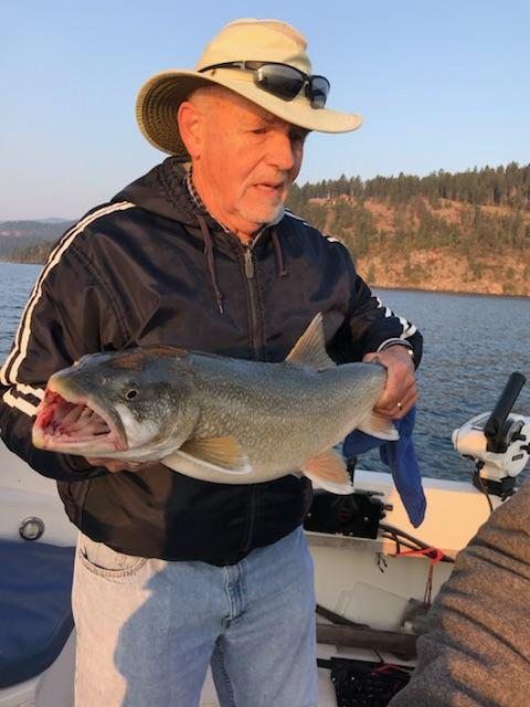 A man in a hat is holding a large fish