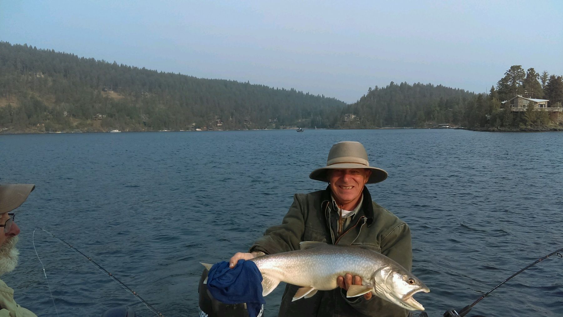 A man in a boat is holding a large fish in his hands.