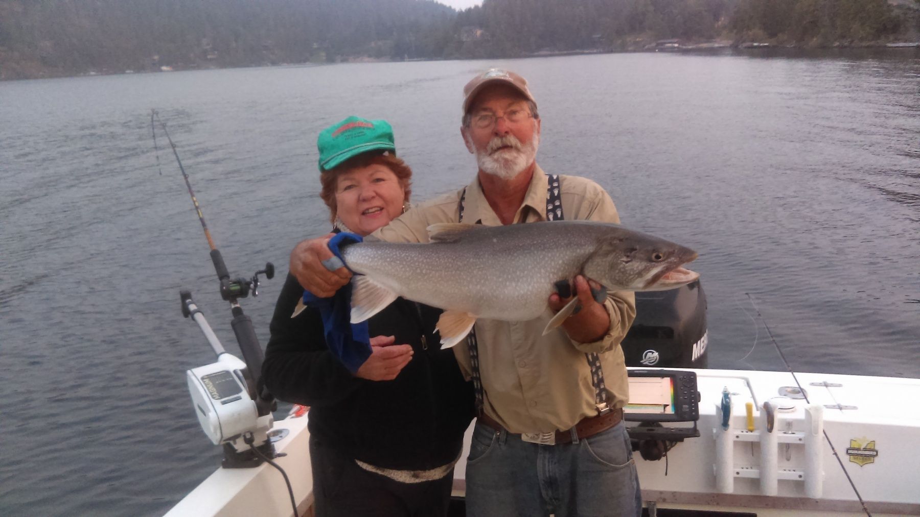 A man and woman holding a large fish on a boat