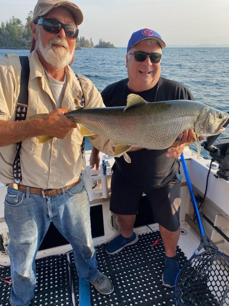 Two men are standing on a boat holding a large fish.