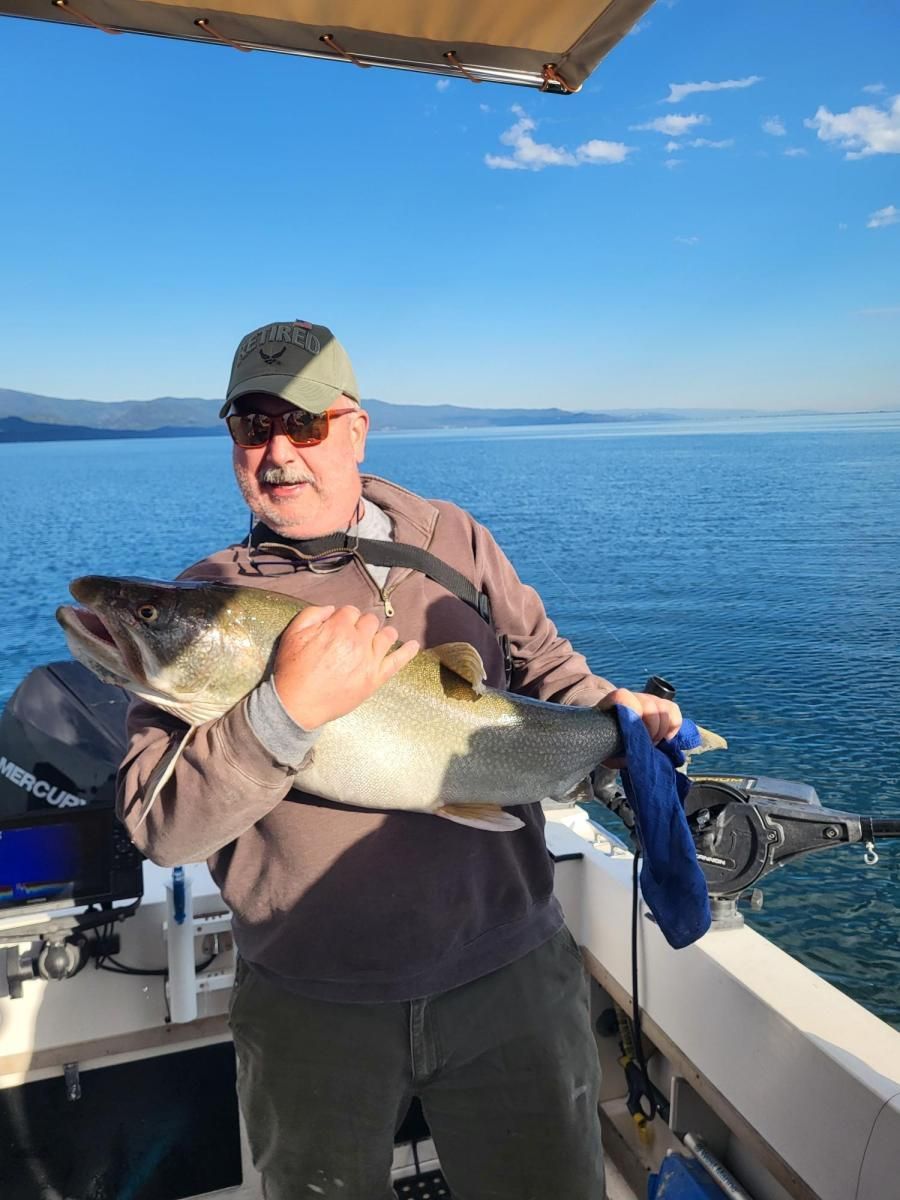 A man is holding a large fish on a boat in the ocean.
