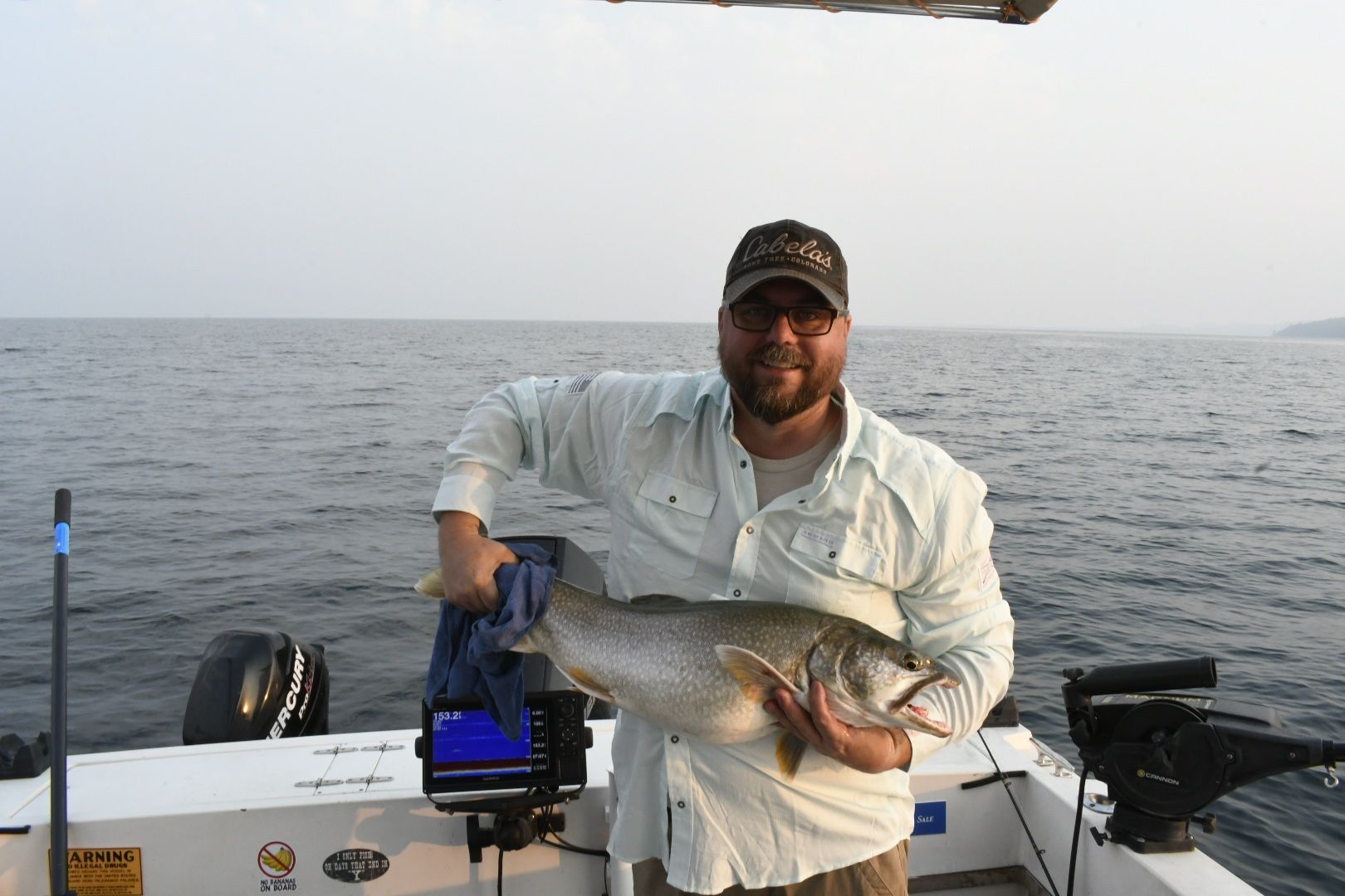 A man is holding a large fish on a boat in the ocean.