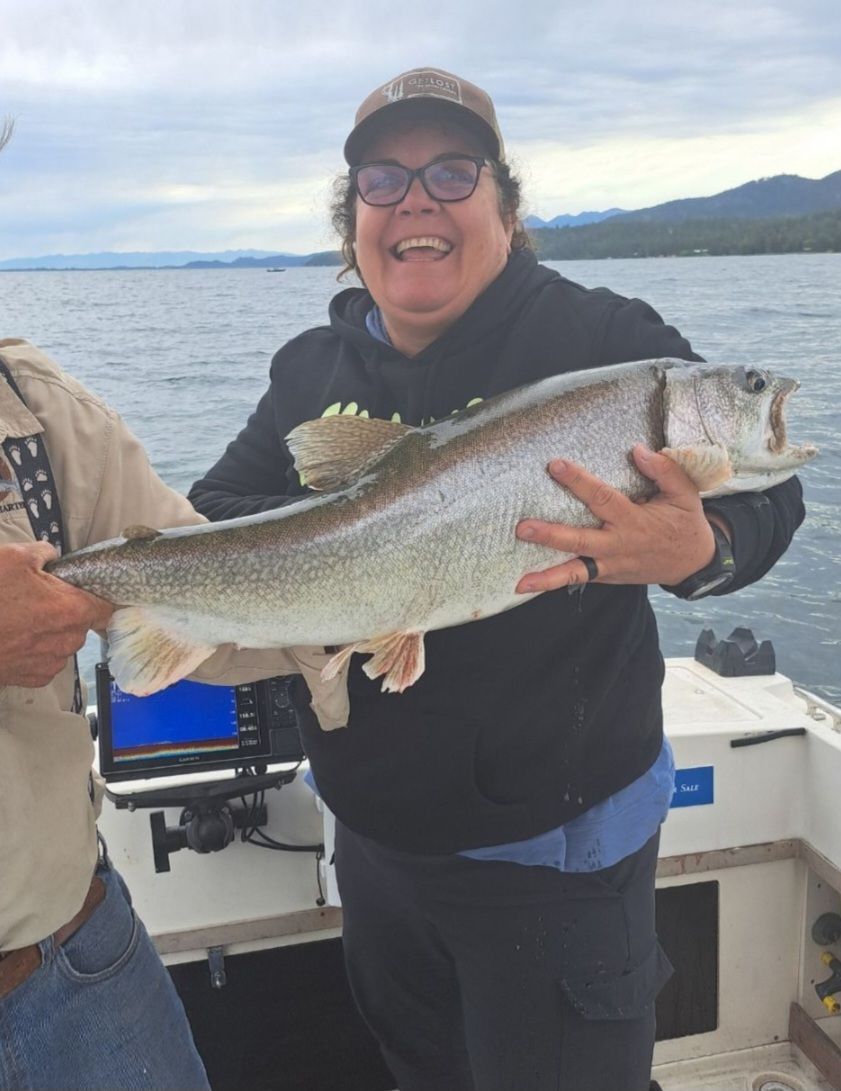 A woman is holding a large fish on a boat