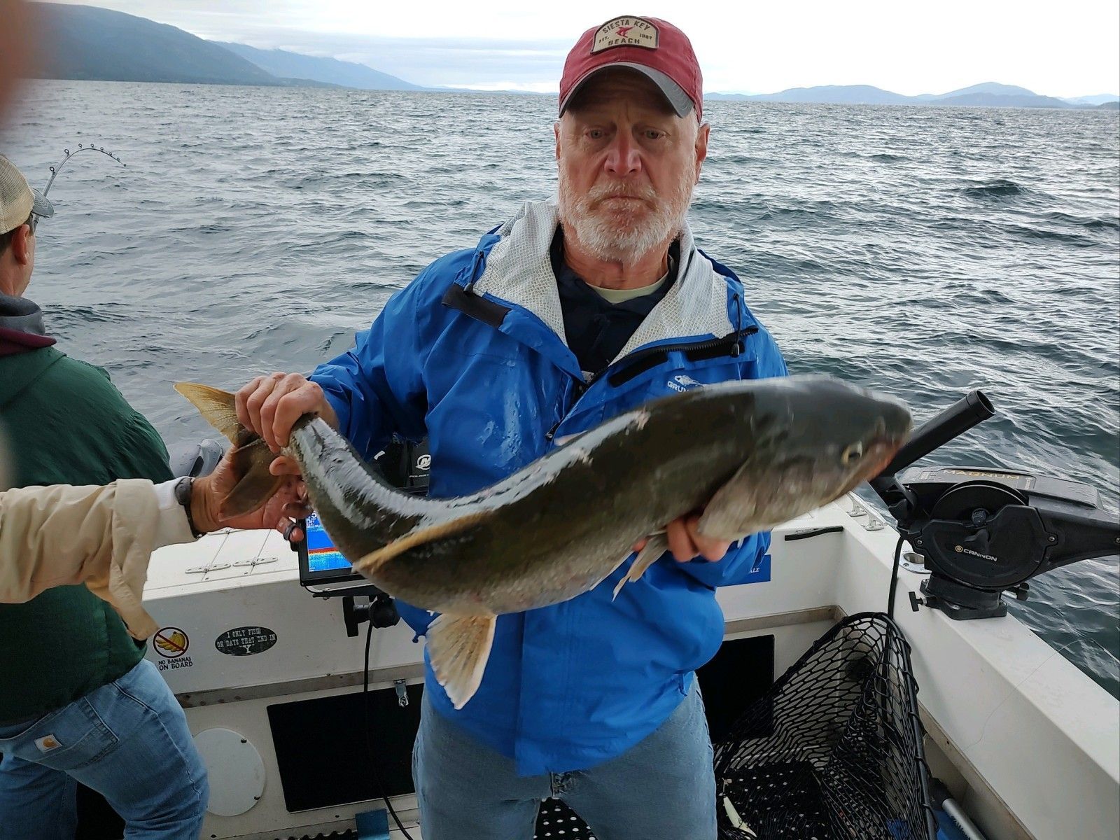 A man is holding a large fish on a boat.