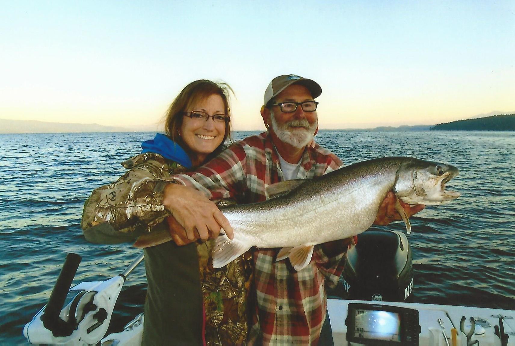 A man and a woman holding a large fish on a boat