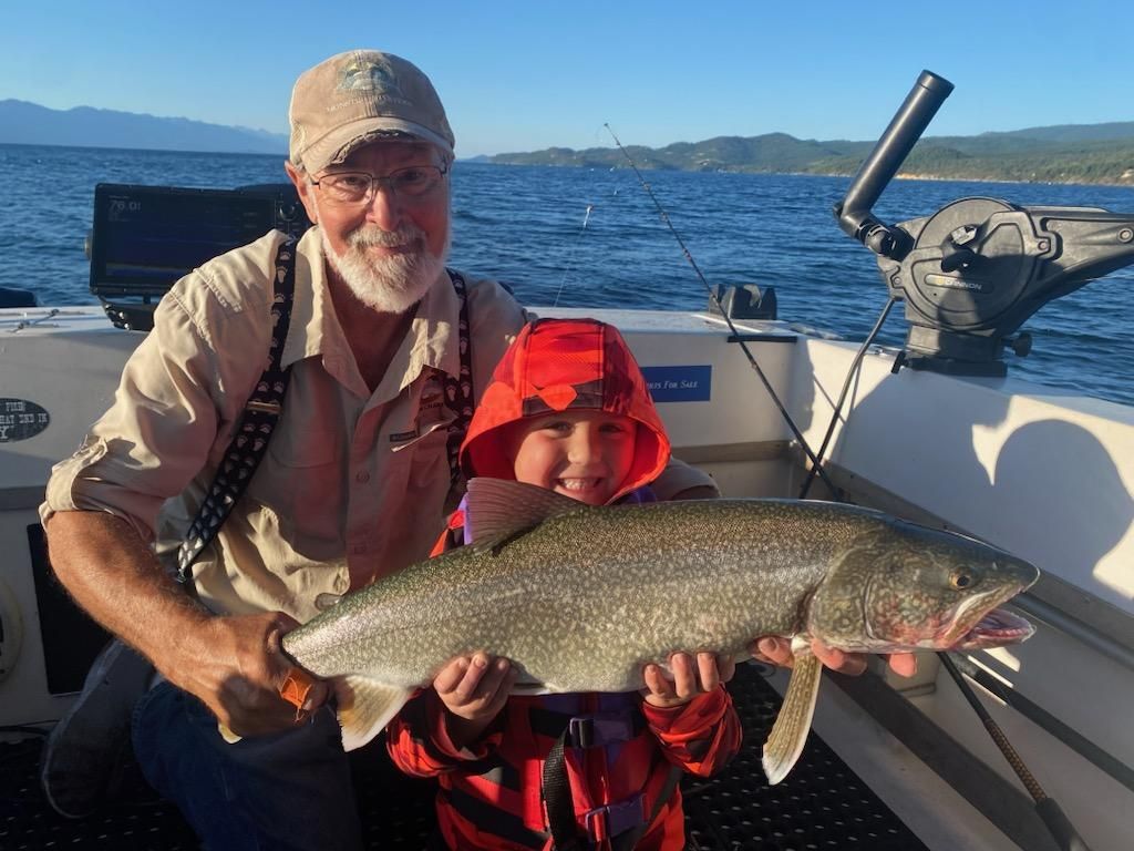 A man and a child are holding a large fish on a boat.