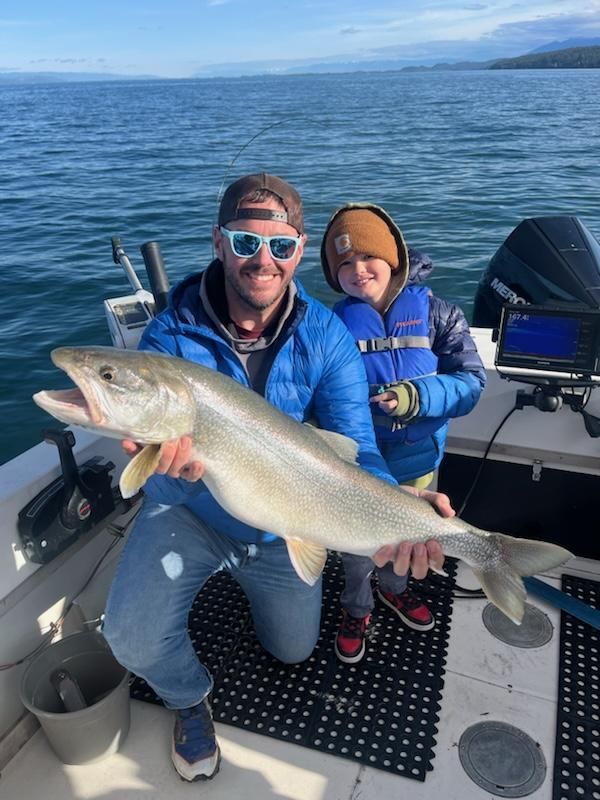 A man and a boy are holding a large fish on a boat.