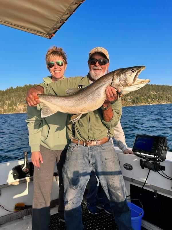 A man and a woman are holding a large fish on a boat.